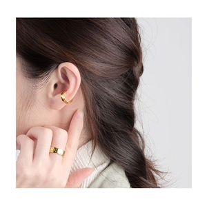 Λεπτομερής λήψη από χρυσό σκουλαρίκι ear cuff και δαχτυλίδι με καπιτονέ σχέδιο σε μοντέλο