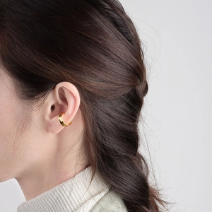 Elegante ear cuff dorado en forma de C con diseño minimalista en la oreja de mujer