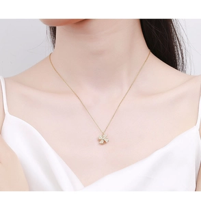 Close-up of a rotating windmill necklace in gold finish worn on a white dress