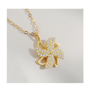 Detail of a rotating golden windmill pendant with sparkling zircons and fine link chain