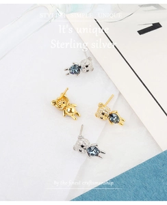Detailed macro of 925 sterling silver bear stud earrings with blue crystal and pavé stones