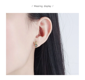 Macro shot of gold-plated bear stud earring with zircon inlay and grey crystal center
