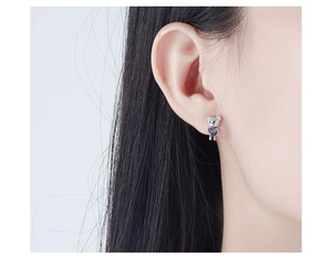 Close-up of heart-shaped blue crystal bear earrings on a model showing fine silver details