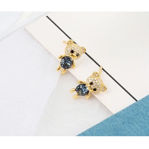 Close-up of golden bear stud earrings with blue crystal and micro-pave diamond details