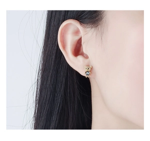 Detail of a gold bear stud earring with tiny white zircons and a round grey stone on ear
