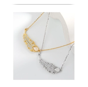 Detail of silver and gold feather necklaces with micro-pave stones and teardrop gems