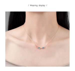 Close-up of S925 sterling silver rose gold kissing fish necklace with blue crystals