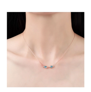 Close-up of S925 sterling silver kissing fish necklace with blue crystals on neck