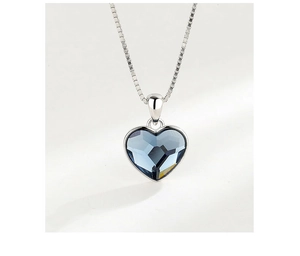 Macro view of blue heart crystal pendant with polished silver frame and box chain