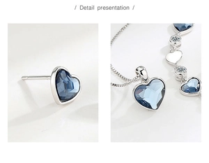 Detailed view of heart-shaped blue crystal pendant and earrings set in silver finish