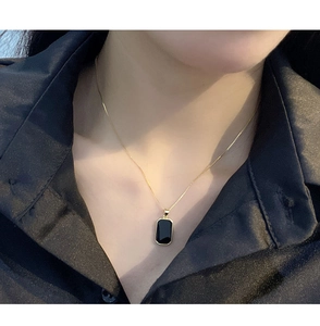 Detail of a vintage S925 silver square pendant necklace worn on a woman neck