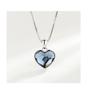 Macro detail of heart-shaped blue crystal pendant on silver box chain necklace