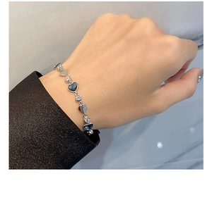 Close-up of a silver heart bracelet with blue crystals on a woman's wrist