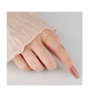 Macro detail of minimalist gold textured ring worn with elegant lace sleeve background