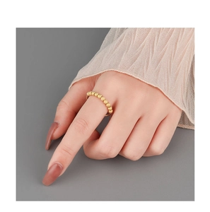 Detail of minimalist gold bead ring on hand featuring matte textured rotating spheres
