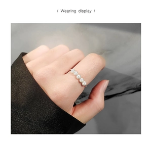 Detailaufnahme eines Sterling Silberrings mit fünf Perlen am Zeigefinger einer Frau