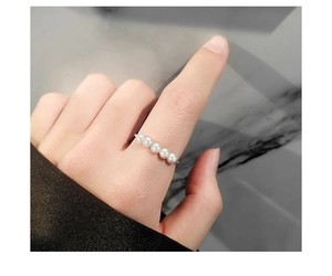 Nahaufnahme von fünf weißen Perlen auf einem silbernen Anti-Stress-Ring am Zeigefinger