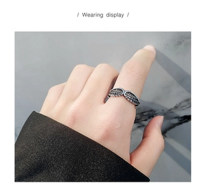 Macro detail of retro oxidized S925 sterling silver angel wing ring with feather texture