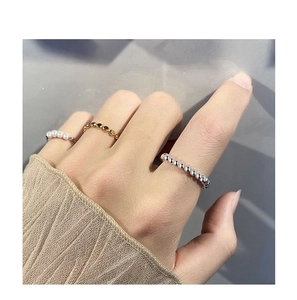 Dettaglio di anelli a fascia in argento 925 con perline dorate e piccole perle bianche