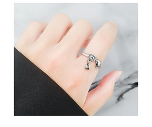 Close-up of S925 sterling silver ring featuring vintage skull and bell charms on finger