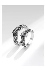 Detailed close-up of retro silver feather wings couple rings with vintage carved texture