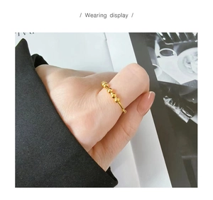 Muestra de uso de un anillo de oro minimalista con cuatro cuentas móviles en el dedo
