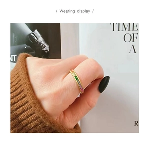Close-up of a gold-tone ring with rainbow baguette-cut zircons worn on a finger
