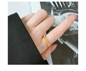 Primer plano detallado de un anillo minimalista de cuentas doradas en el dedo con fondo de revista