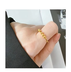 Detalle de anillo antiestrés dorado con 5 cuentas móviles puesto en el dedo mujer