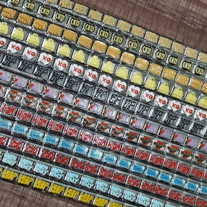 Nahaufnahme der personalisierten 9mm Edelstahl-Charms mit bunten Emaille-Motiven