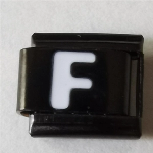 Macrodetail van een Italiaanse armbandmodule met witte letter F op zwart roestvrij staal