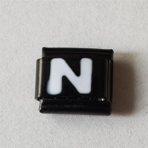 Detail van een vierkante modulaire bedel met witte letter N op zwarte lak