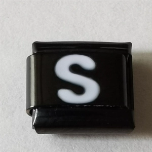 Macro-opname van zwart roestvrijstalen Italiaanse charm met de witte letter S erop