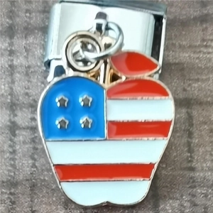 Macro view of apple-shaped enamel charm with American flag design and silver metal clasp