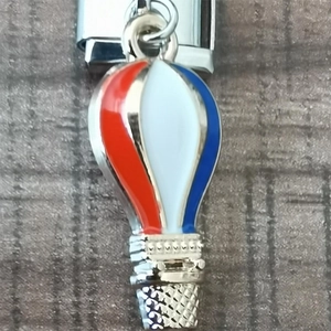 Macro detail of red, white, and blue hot air balloon charm on a stainless steel link
