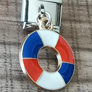 Macro detail of a nautical lifebuoy charm in red and blue on a modular stainless steel link