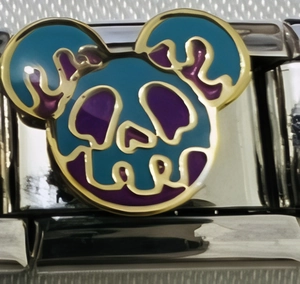 Makroaufnahme von Edelstahl-Charm mit blau-violettem Totenkopf-Design und Goldkonturen