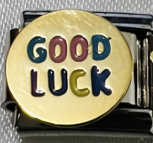 Detailansicht eines Good Luck Charms mit bunten Buchstaben auf goldener Oberfläche