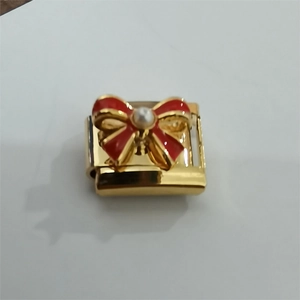 Makroaufnahme von 18K Gold-Modulglied mit roter Emaille-Schleife und weißer Perleneinlage