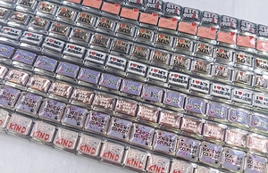 Macro detail of various stainless steel DIY Italian charms with engraved emotional slogans