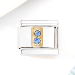 Detail of silver modular charm with golden patch and two blue zircon stones