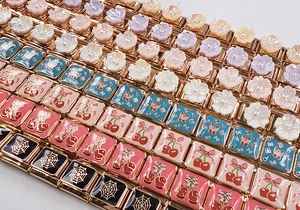 Vue détaillée des charms modulaires en or 18K avec motifs floraux et émail perlé