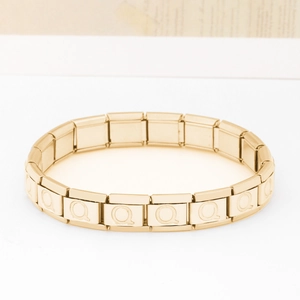 Dettaglio macro del bracciale componibile in acciaio dorato con incisioni della lettera Q