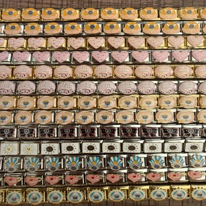 Detail of Italian charm links with colorful enamel patterns like Eye of Horus and I Love Mom