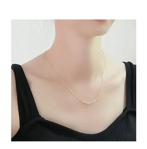 Detail van de gebogen gouden hanger bezet met vijf zirkonia's op een sleutelbeenketting
