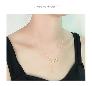 Dettaglio di una collana a foglia dorata con pendente trasparente indossata da una modella