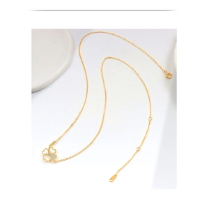 Detailansicht der goldenen Kleeblatt-Halskette mit weißer Muschel und kleinem Kristall