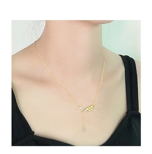 Elegante collana in argento S925 dorato con ciondoli a foglia e pendente a goccia su modella