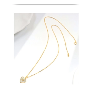 Gedetailleerde close-up van de gouden hartvormige hanger met letter M en zirkonia