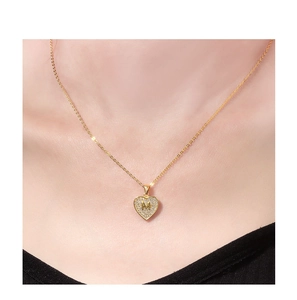 Detail van een 18K vergulde hartketting met een gezette zirkonia M-letter op model